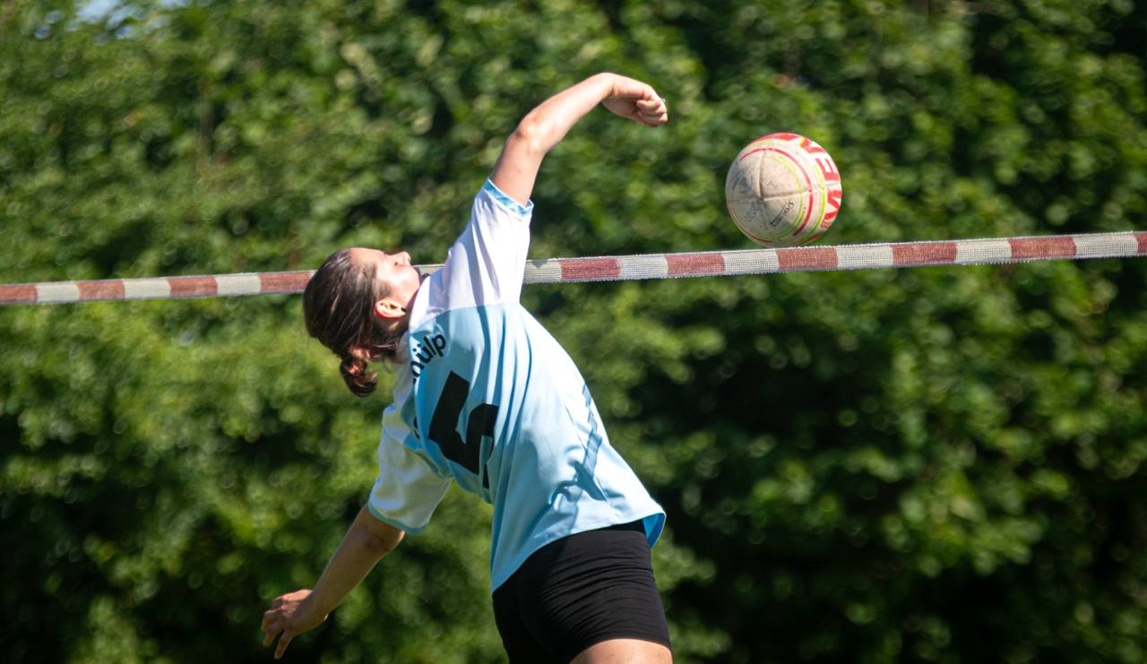 Faustball-Spielerin des TSV Schülp beim Schlag am Netz gegen grünen Hintergrund.