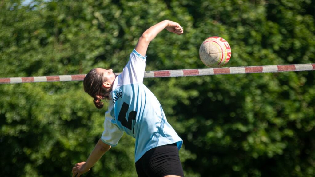 Faustball-Spielerin des TSV Schülp beim Schlag am Netz gegen grünen Hintergrund.