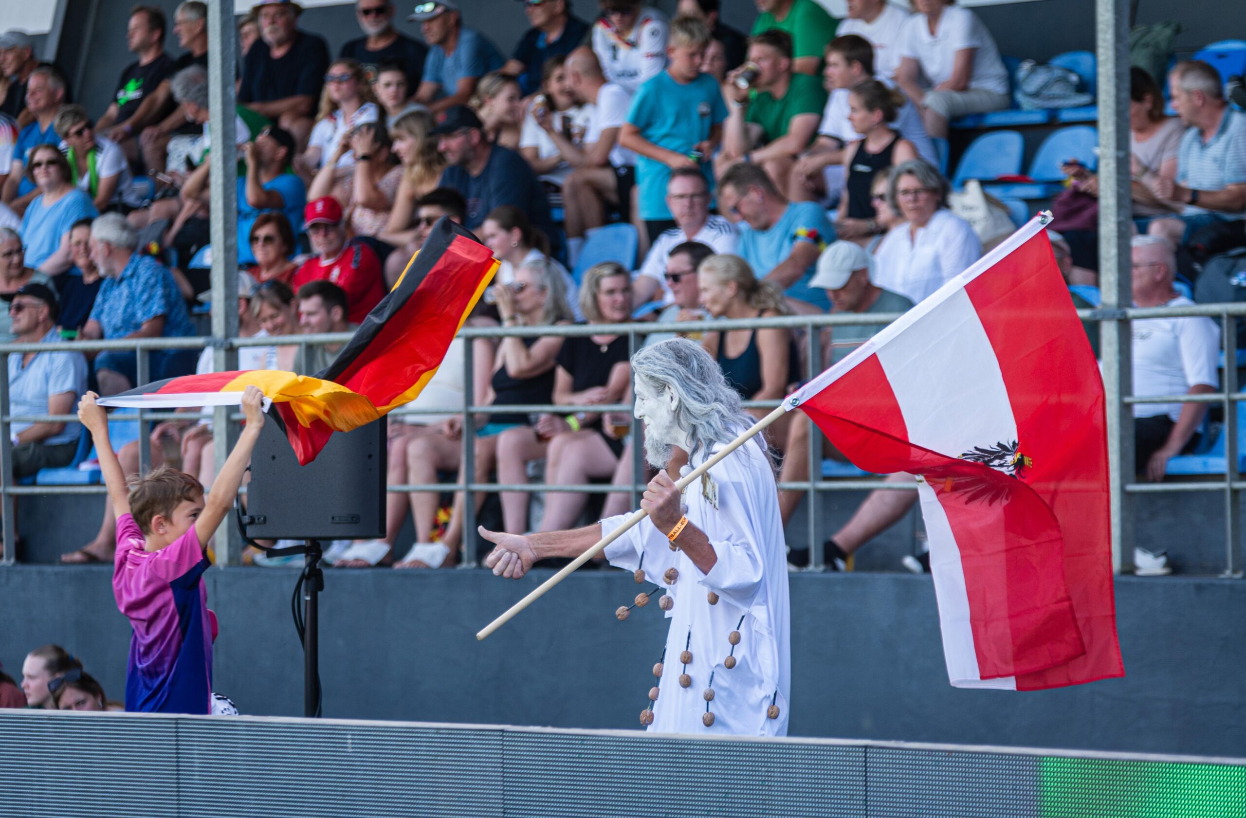 Der Nussgeist und Kinder mit Deutschland- und Österreichfahnen vor der vollen Tribüne in Tondern