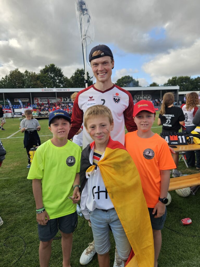 Drei Kinder mit Deutschlandfahne und einem österreichischen Faustball-Nationalspieler in Tondern