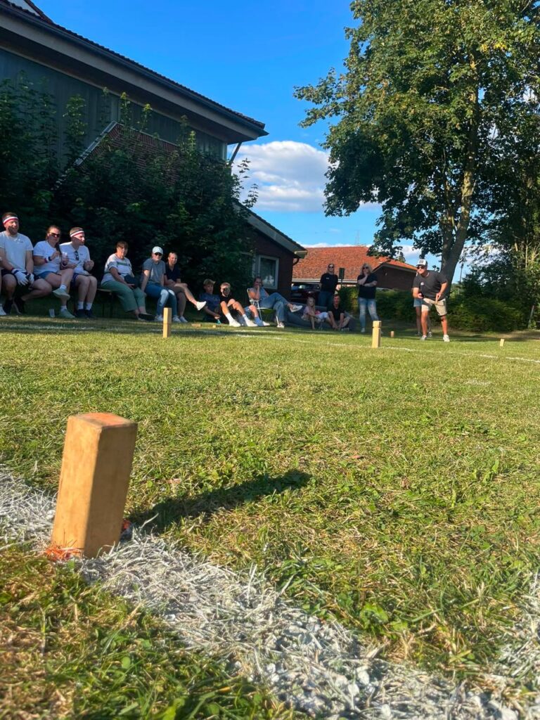 Kubbs im Vordergrund und Spieler am anderen Feldende