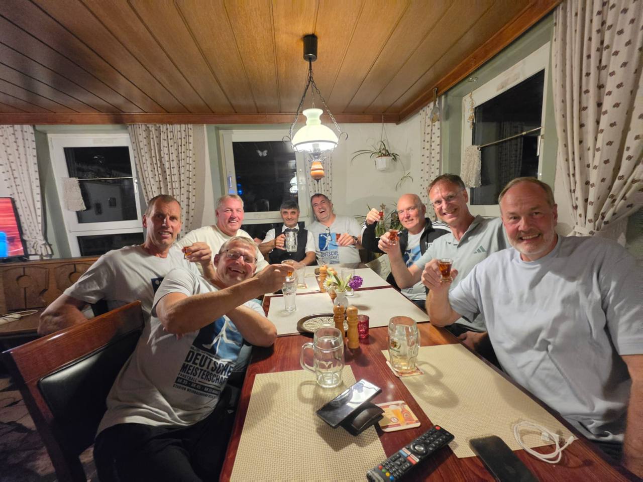 Acht Männer sitzen in einer Gaststätte gemeinsam am Tisch und stoßen nach dem Turniertag an