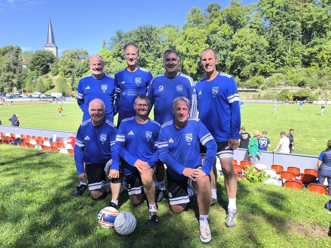 Sieben Faustballspieler des TSV Schülp in blauen Trikots als Mannschaft auf der Sportanlage in Veilsdorf