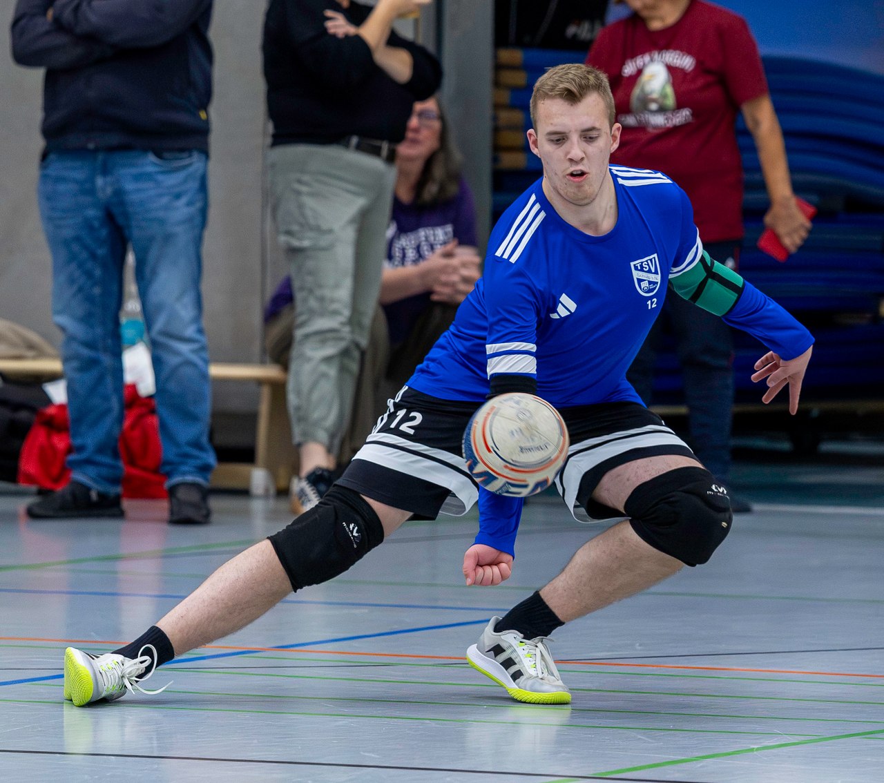 Ein Schülper Faustballspieler mit Knieschonern nimmt den Ball in tiefem Ausfallschritt an.