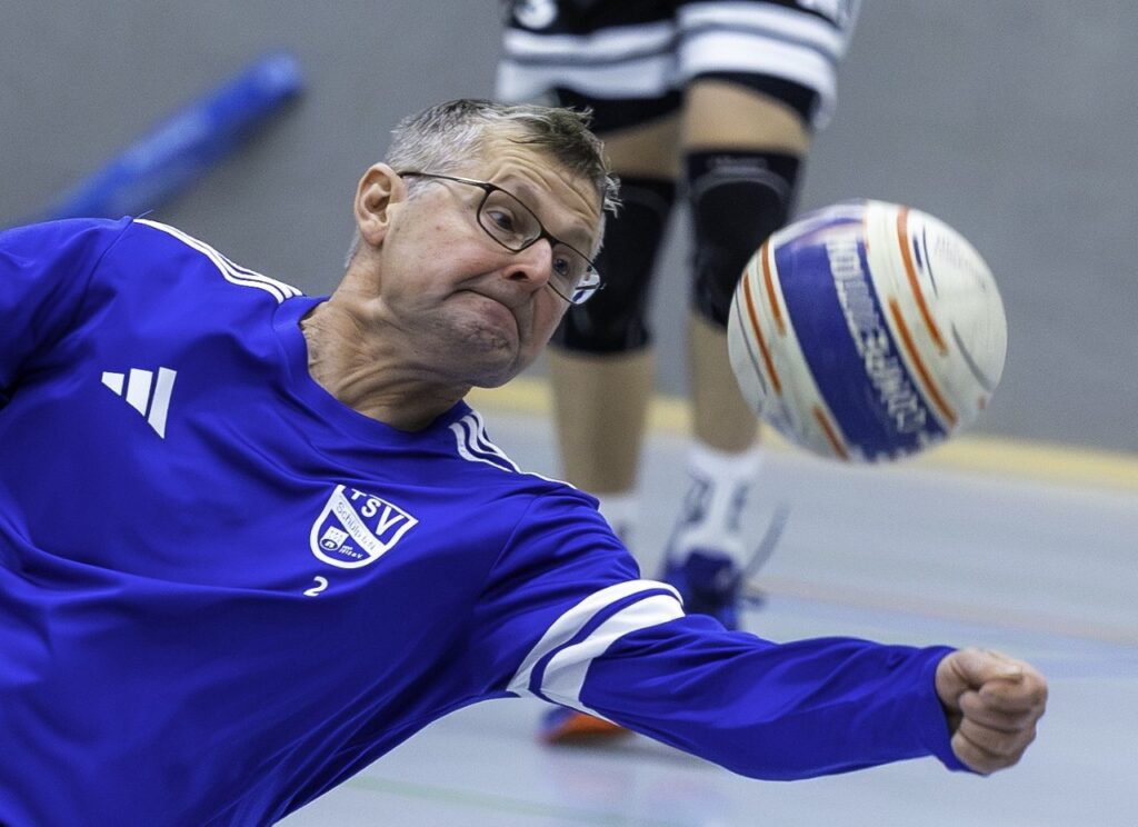 Nahaufnahme eines Schülper Faustballspielers im blauen Trikot beim Spielen des Balls mit gestrecktem Arm.